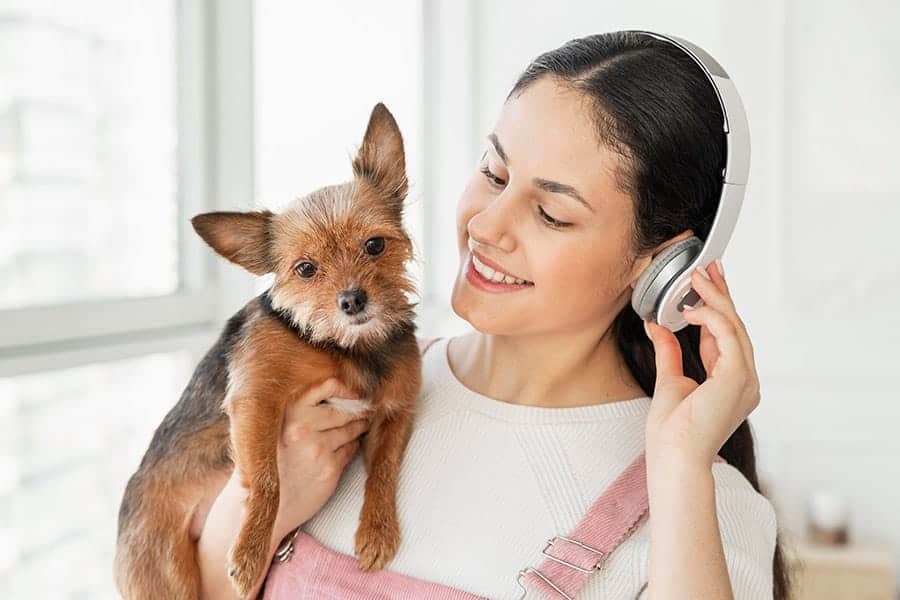 chica con auriculares sosteniendo un perro