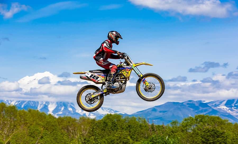 un piloto de motocross volando en el aire con montañas